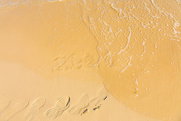 New Year 2021 is coming - inscription 2021 on a beach sand, the wave is cover the digits and footsteps - Summer beach holiday 2021 season golden sand - message handwritten empty copy space footprints