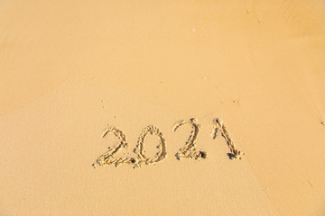 New Year 2021 is coming - inscription 2021 on a beach sand, the wave is starting to cover the digits - Summer beach holiday 2021 season golden sand - old year - message handwritten - empty copy space