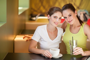 Portrait of young attractive women sitting while drinking in coffee shop