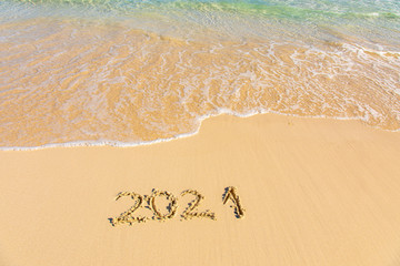 New Year 2021 is coming - inscription 2021 on a beach sand, the wave is starting to cover the...