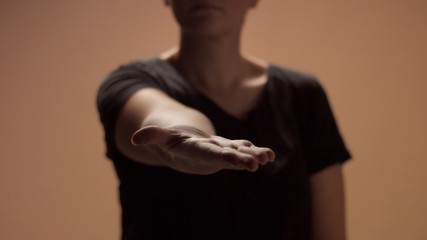 unrecognizible woman out of focus holds out her hand towards to the camera to focus zone to compose something above her hand
