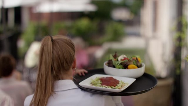 Waitress Walking to Outdoor Table With Plate of Food