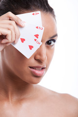 Portrait of young Mixed Race woman covering her eye with playing card against white background