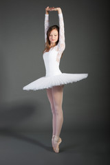 Young female ballet dancer posing over grey background © MDBPIXS