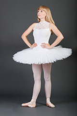 Young female ballet dancer with hands on hips standing over grey background © MDBPIXS