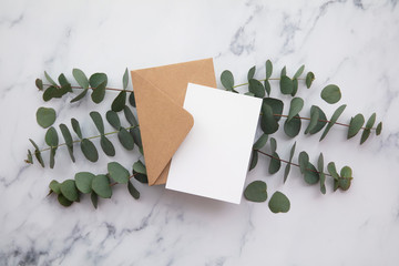 Blank white card and envelope with eucalyptus leaves. Blank invitation.