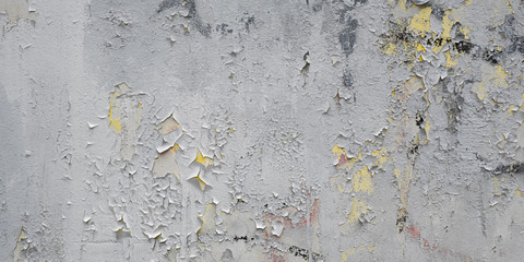 Gray Dirty Plaster Wall, With Falling Off Flakes Of Paint. Rough Surface. Old Weathered Painted Background Texture. Panoramic Wide Background. Peeled Plaster Wall.