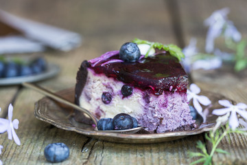 Slice of Blueberry flavour cheesecake swirled with blueberry sauce on a  biscuit crumb, bakery. Delicious slice of blueberries cheesecake with  jam and green mint.  Sweet and tasty food, coffee break 