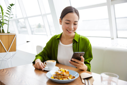 Smiling asian woman having pancakes for breakfast