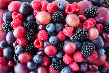 Background of fresh vegetables and fruits. Ripe blackberries, blueberries, plums, pink grapes, raspberries. Mix berries and fruits. Top view. Background berries and fruits.Black-blue and red food.
