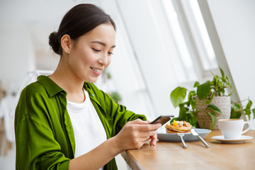 Smiling asian woman having pancakes for breakfast