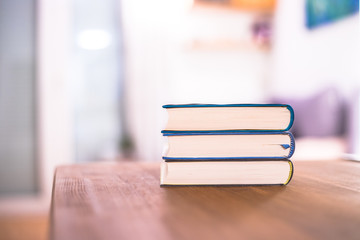 Knowledge and science concept: Stack of books lying on wooden desk, home.