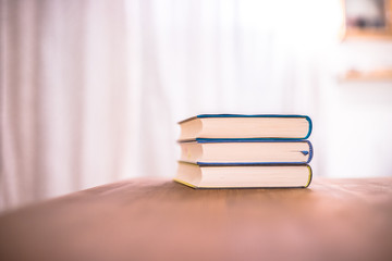 Knowledge and science concept: Stack of books lying on wooden desk, home.