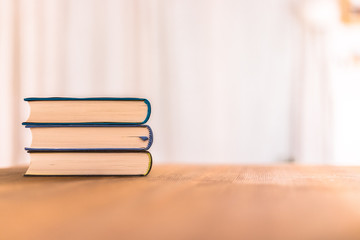Knowledge and science concept: Stack of books lying on wooden desk, home.
