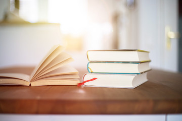 Knowledge and science concept: Stack of books lying on wooden desk, home.