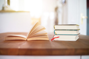 Knowledge and science concept: Stack of books lying on wooden desk, home.