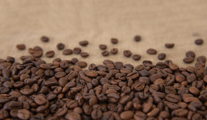 Fototapeta na wymiar Freshly roasted coffee beans sprinkled with beans on burlap with copy space for text