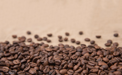 Freshly roasted coffee beans sprinkled with beans on burlap with copy space for text