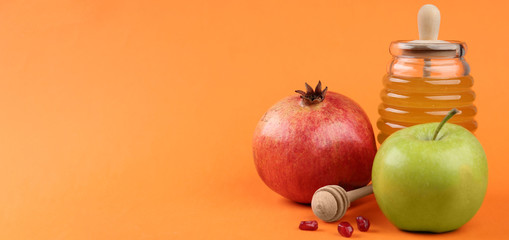 Honey, apples and pomegranate on orange background, space for text. Rosh Hashanah holiday