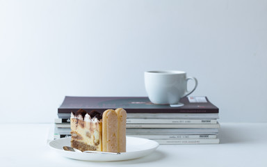 Slice of  Tiramisu dessert on stack book.  Fresh Birthday Cake. Isolated on white. Room for text. Clipping Path.  Valentines day, mothers day, womens day, wedding concept. Flat lay, top view, copy 