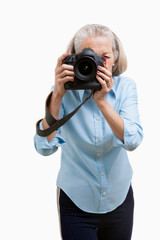 Senior female photographer using camera against white background