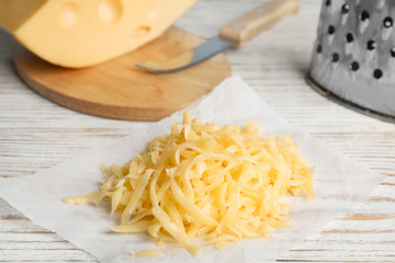Tasty grated cheese on white wooden table