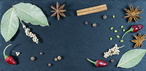 Stone board with various spices on a dark background