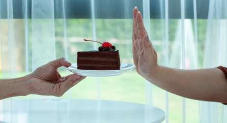 The woman refuses to eat the chocolate cake on the hand. Stop eating sweets to lose weight