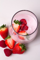 glass with yogurt and fresh berries on a white background top view