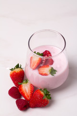 glass with yogurt and fresh berries on a white background