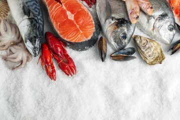 Fresh fish and seafood on ice, flat lay. Space for text