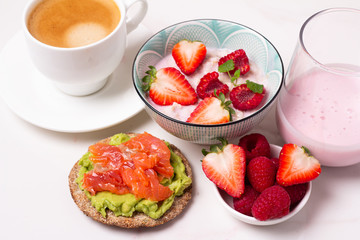 breakfast of porridge with berries, coffee and yogurt and toast top view
