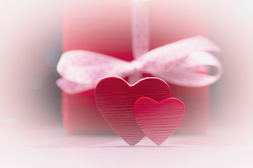 Two red hearts over defocused gift box. Valentines day background