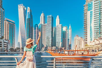 Fröhliches asiatisches Reisendes Mädchen, das auf einer Promenade im Stadtteil Dubai Marina spazieren geht. Reiseziele und touristischer Lebensstil in den VAE
