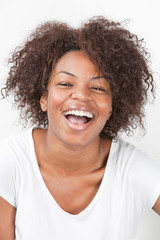 Portrait of a joyful African American young woman laughing against white background