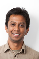 Portrait of young Indian man smiling against white background