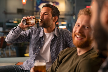 Man with friends drinking a bottle of beer