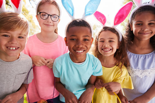 Portrait Of Five Children Wearing Bunny Ears On Easter Egg Hunt In Garden - Powered by Adobe