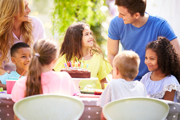 Parents And Daughter Celebrating Birthday With Friends Having Party In Garden At Home