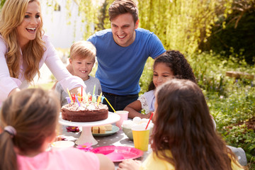 Parents And Son Celebrating Birthday With Friends Having Party In Garden At Home