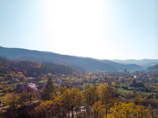 Aerial view of the small village of Sheshory, surrounded by the Carpathian mountains. Buildings and infrastructure. The nature of Ukraine. Sunny autumn day. Huk waterfall on the Pistynka River.