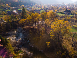 Aerial view of the small village of Sheshory, surrounded by the Carpathian mountains. Buildings and infrastructure. The nature of Ukraine. Sunny autumn day. Huk waterfall on the Pistynka River.