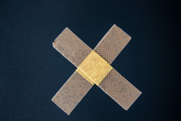 Adhesive bandage against a black background. Medical adhesive bandage stock image. Image of medical plaster glued like a cross