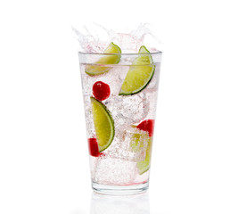 Clear glass of carbonized clear liquid with ice cubes, cherries, and lime wedges in the glass