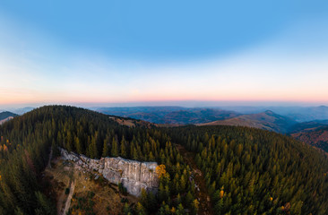Aerial view of the Recreation Mountain Pysany kamin in Carpathian mountains. autumn. Pine forest, houses on the peaks, yellow fields and trees. Mountain meadow. sunset, Ukraine