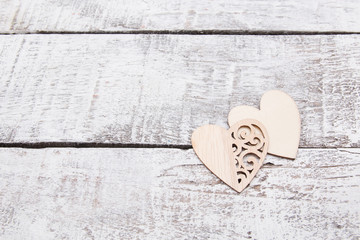 wooden hearts on gray boards, copy space, aged wooden plank background painted white, wood texture, natural material, love on Valentine's Day concept, laser cut out heart patterns