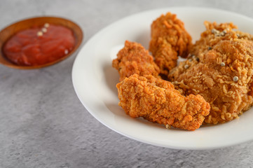 Crispy fried chicken on a white plate with tomato sauce.