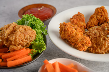 Crispy fried chicken on a white plate with tomato sauce and carrot,