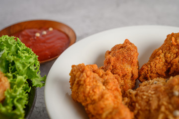 Crispy fried chicken on a white plate with tomato sauce and carrot,