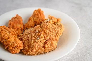 Crispy fried chicken sprinkled with pepper seeds on a white plate, Selective focus.